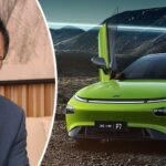 En man i kostym och slips sitter bredvid en grön bil. (AI text)