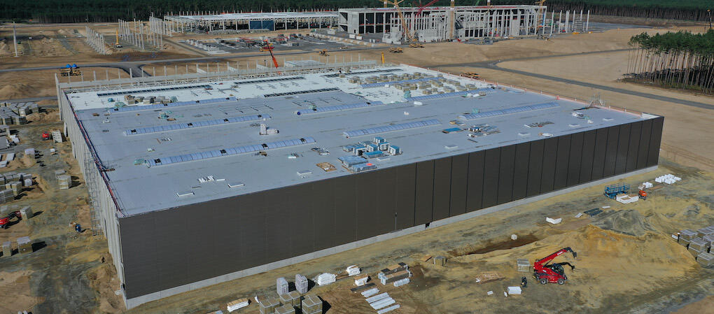 En byggarbetsplats med ett stort byggnad i bakgrunden. (AI text)