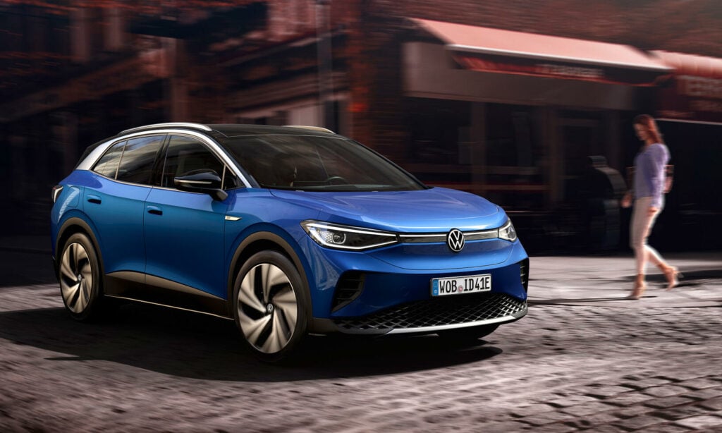 En blå Volkswagen e-tron kör nerför en stadsgata. (AI text)
