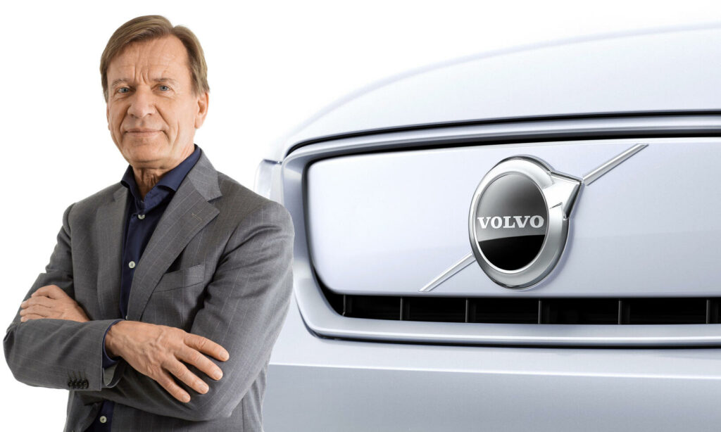 En man i kostym står bredvid en Volvo-bil. (AI text)