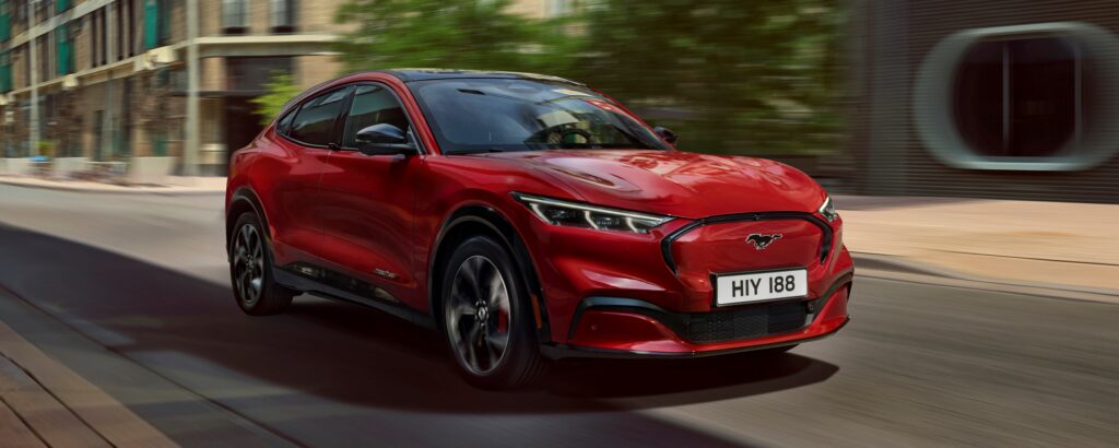 En röd SUV kör nerför en stadsgata. (AI text)