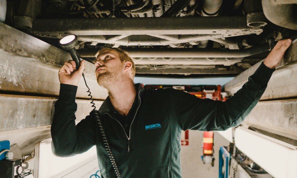 En mekaniker arbetar på en bil under huven. (AI text)