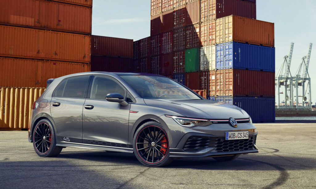 Volkswagen Golf R står parkerad framför en containerskepp. (AI text)