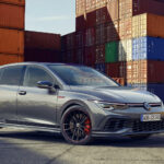 Volkswagen Golf R står parkerad framför en containerskepp. (AI text)