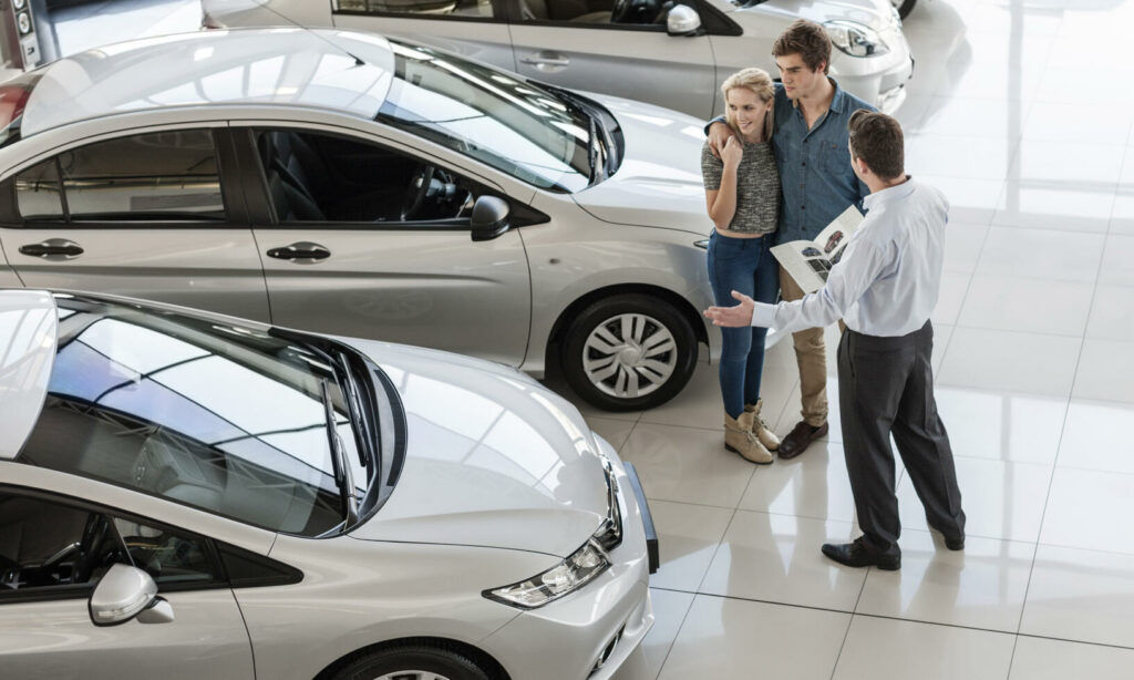 En man och en kvinna tittar på bilar i en showroom. (AI text)