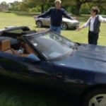 En man och kvinna står bredvid en Chevrolet Corvette. (AI text)