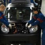 Två män arbetar på en bil i en fabrik. (AI text)