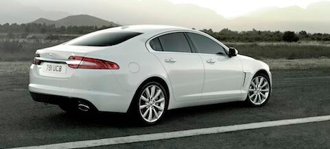 En vit Jaguar XF parkerad vid vägkanten. (AI text)
