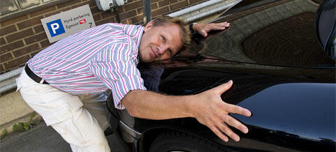 En man lägger sig mot en bil. (AI text)