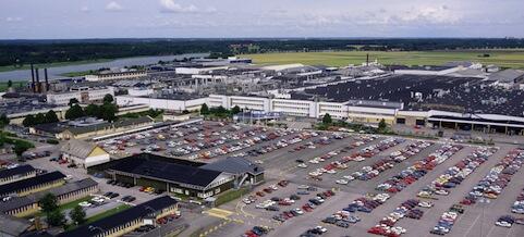 En fabrik med många bilar parkerade i parkeringen (AI text)