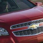 En röd Chevrolet Traverse kör nedför vägen. (AI text)