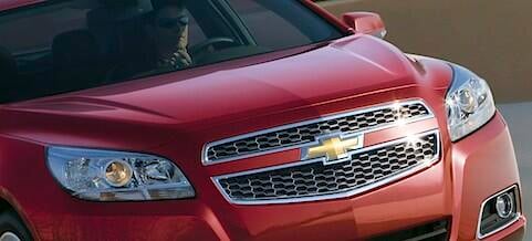 En röd Chevrolet Traverse kör nedför vägen. (AI text)