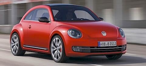 En röd Volkswagen Käfer kör ner vägen. (AI text)