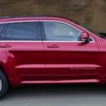 En röd Jeep Grand Cherokee kör nedför en bergsväg. (AI text)