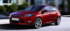 En röd Ford Focus kör nerför en stadsgata. (AI text)
