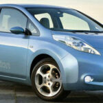 En blå Nissan Leaf parkerad på en gata. (AI text)