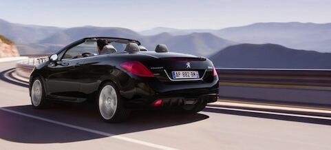 En svart cabriolet kör nedför en bergsväg. (AI text)