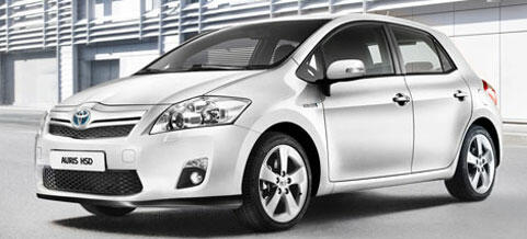 En vit Toyota Auris parkerad framför ett byggnad. (AI text)