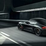 En svart sportbil kör nedför en mörk tunnel. (AI text)