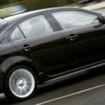 En svart bil kör längs en gata. (AI text)