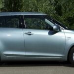 En silverfärgad Suzuki Swift parkerad på en parkeringsplats. (AI text)