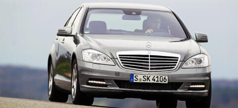 En Mercedes-Benz S-klass sedan kör på en väg. (AI text)
