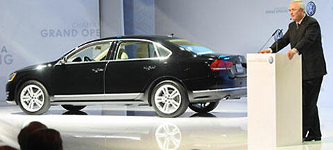 En man står vid ett podie och talar om en bil. (AI text)