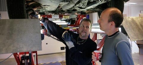 Två män arbetar på en bil. (AI text)