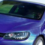 En blå Volkswagen Eos kör nerför vägen. (AI text)