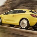 En gul bil kör nedför en bergsväg. (AI text)