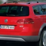En röd Volkswagen-jeep kör nerför en väg. (AI text)