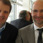 Två män i kostymkläder leker med kameran. (AI text)