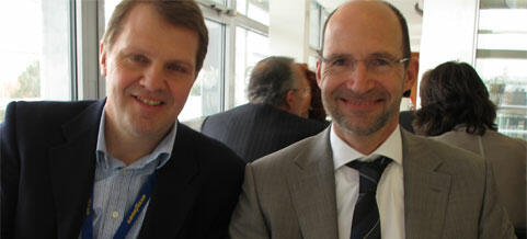 Två män i kostymkläder leker med kameran. (AI text)