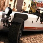 En vit sportbil kör nerför en stenlagd gata. (AI text)