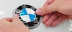 En person undersöker en BMW-logotyp. (AI text)