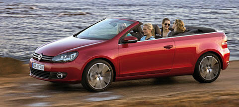 En röd Volkswagen Golf cabriolet kör nerför en stenig väg. (AI text)