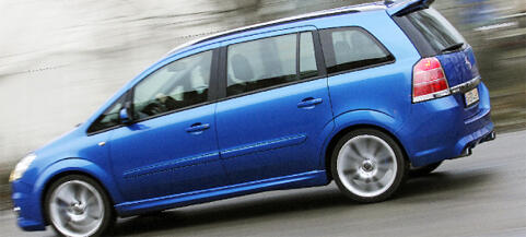 En blå bil kör nedför en gata. (AI text)