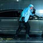 En man står bredvid en bil i en garage. (AI text)