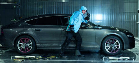 En man står bredvid en bil i en garage. (AI text)