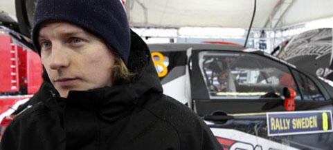 En man i en mössa står bredvid en rallybil. (AI text)