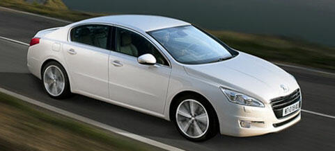 En vit bil kör nedför en väg. (AI text)