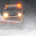 En snöskopa kör nedför en snöig väg. (AI text)