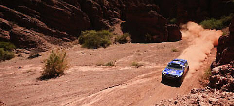 En blå bil kör nedför en grusväg. (AI text)