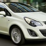 En vit bil körer nerför en stadsgata. (AI text)