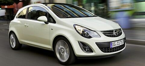 En vit bil körer nerför en stadsgata. (AI text)