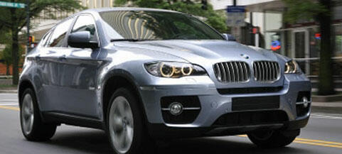 BMW X6 SUV kör ned gatan längs (AI text)