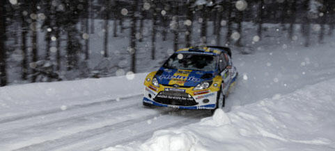 En rallybil kör genom snön. (AI text)