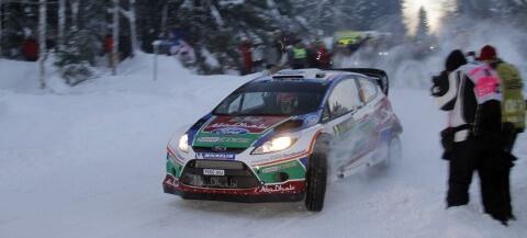En rallybil kör nedför en snöig väg. (AI text)
