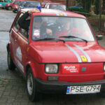 En röd bil parkerad på en gata (AI text)