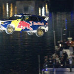 Red Bull-rc-bil flyger över en stad (AI text)